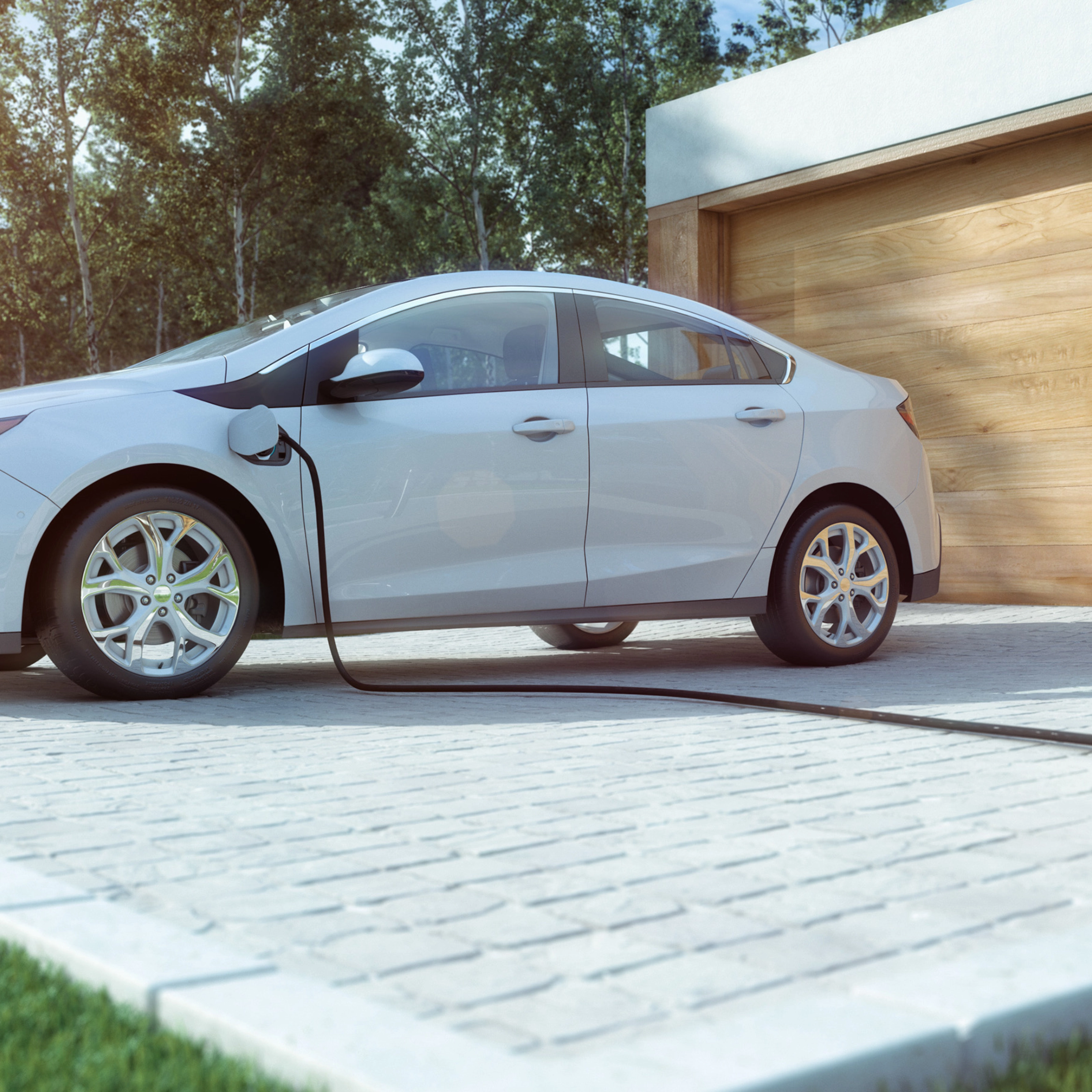 An electric car is charging in front of a modern house with a wooden garage door.