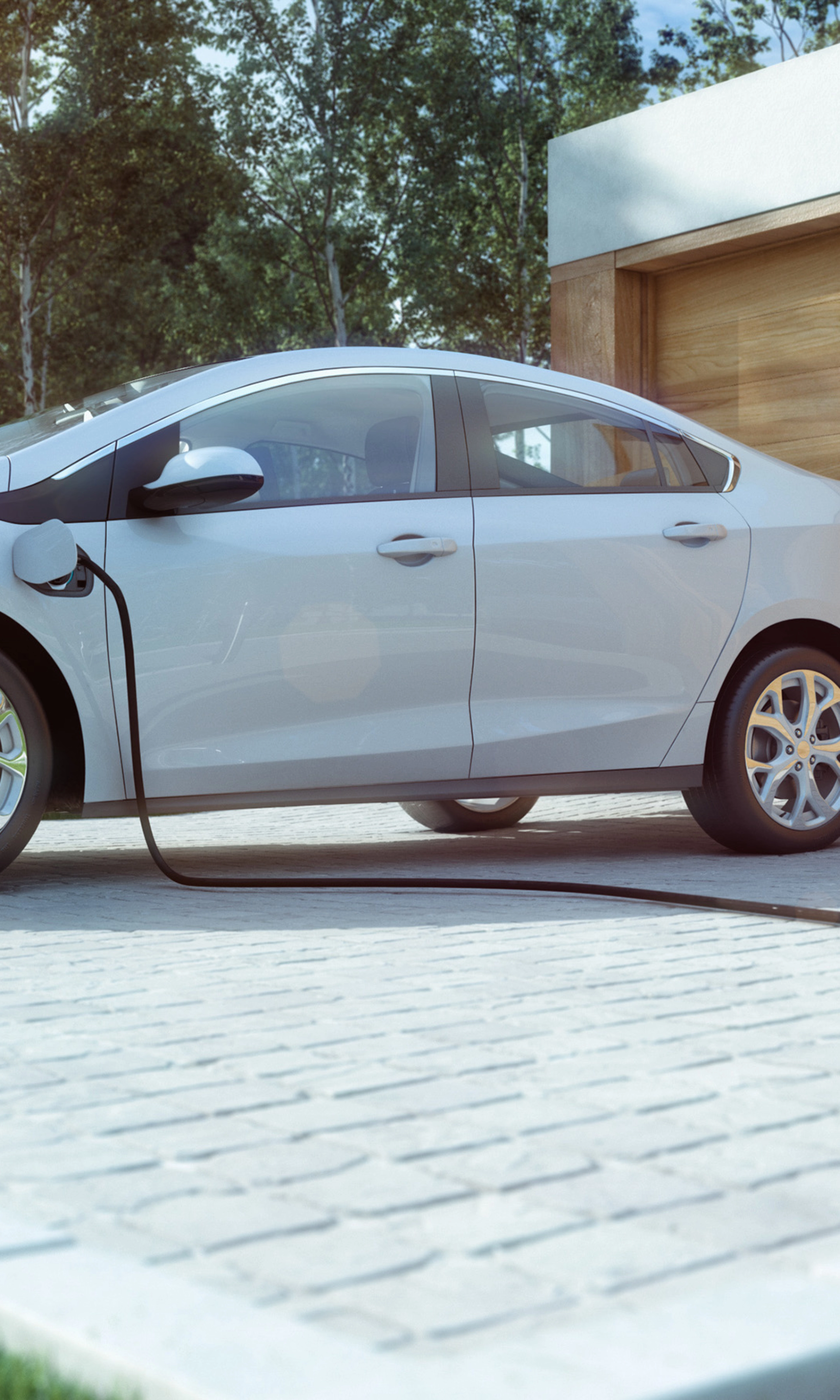 An electric car is charging in front of a modern house with a wooden garage door.
