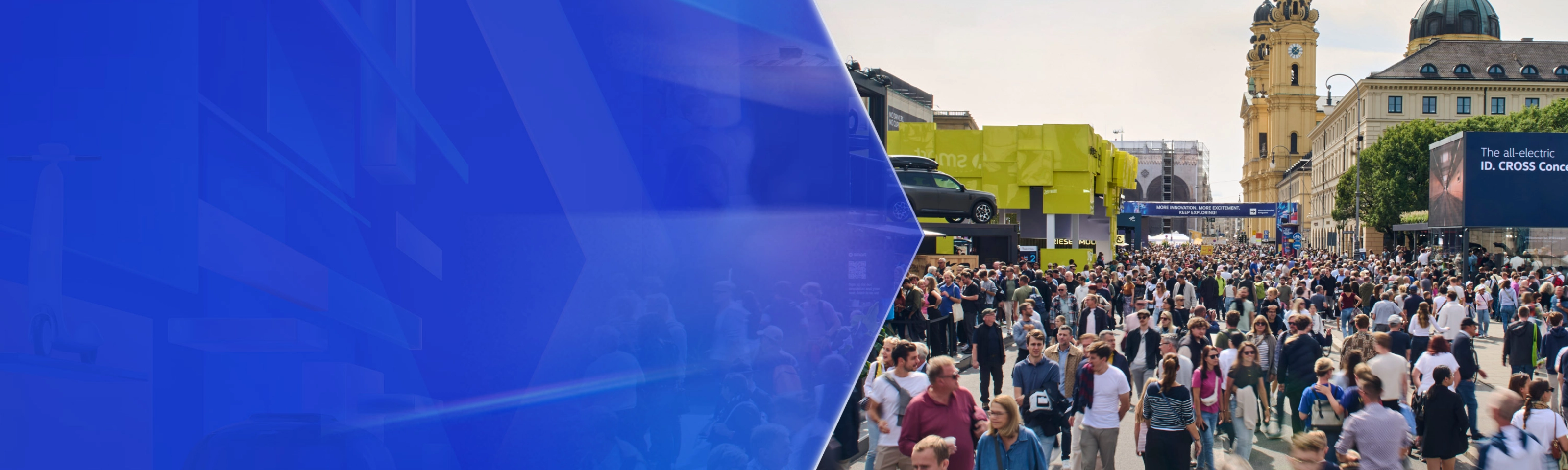 Large crowd at an outdoor mobility fair with exhibition booths and historic buildings in the background.