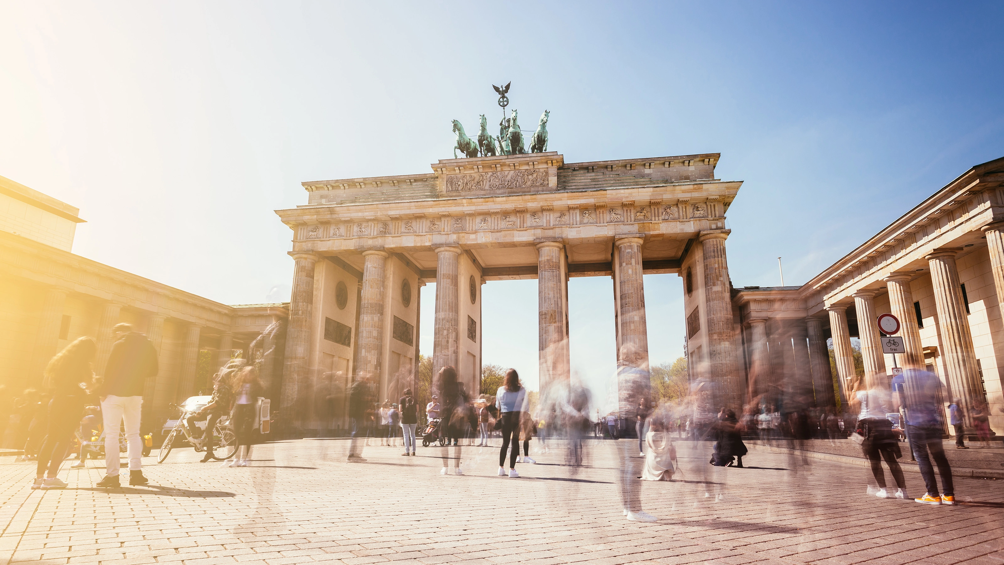 Brandenburg Gate in Berlin with many people in motion on a sunny day.