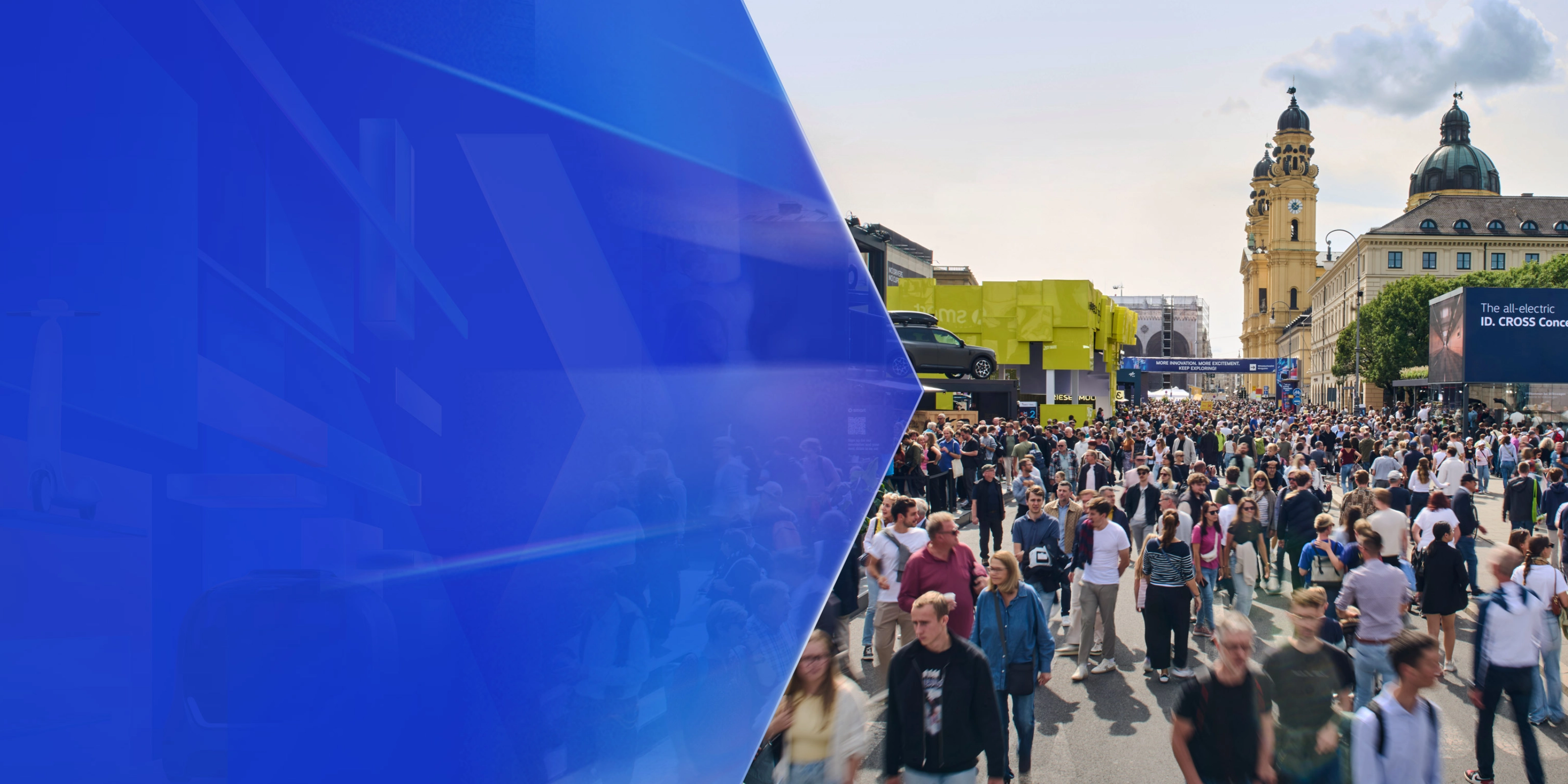 Large crowd at an outdoor mobility fair with exhibition booths and historic buildings in the background.