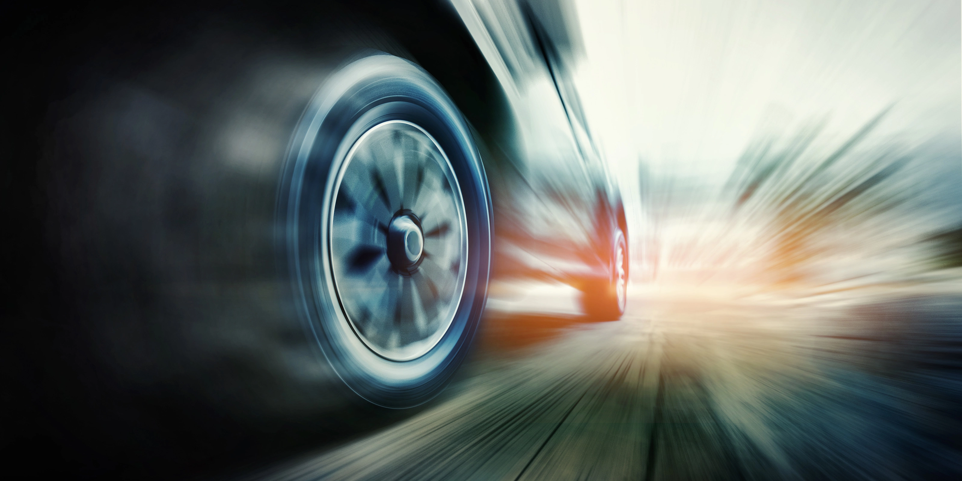 Close-up of a speeding car tire in motion blur on the road.