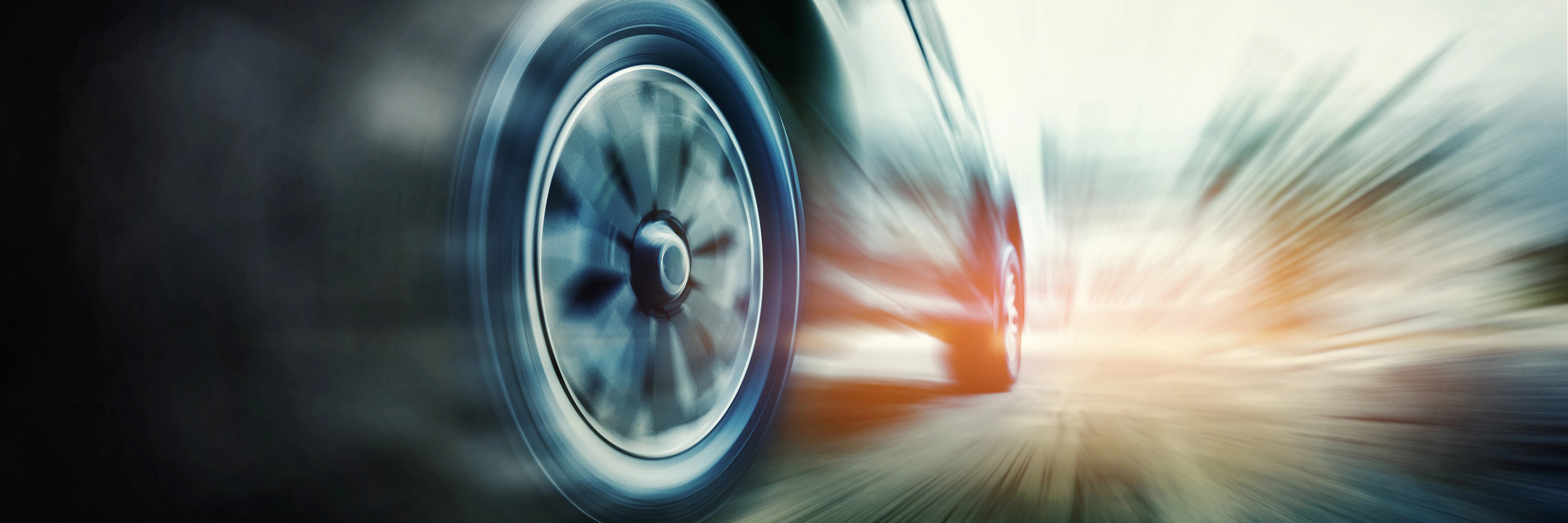 Close-up of a speeding car tire in motion blur on the road.