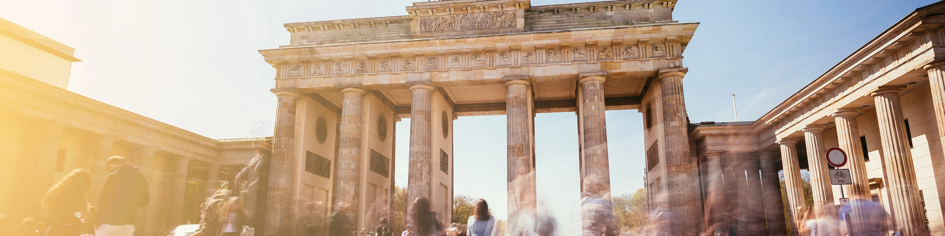 Brandenburg Gate in Berlin with many people in motion on a sunny day.
