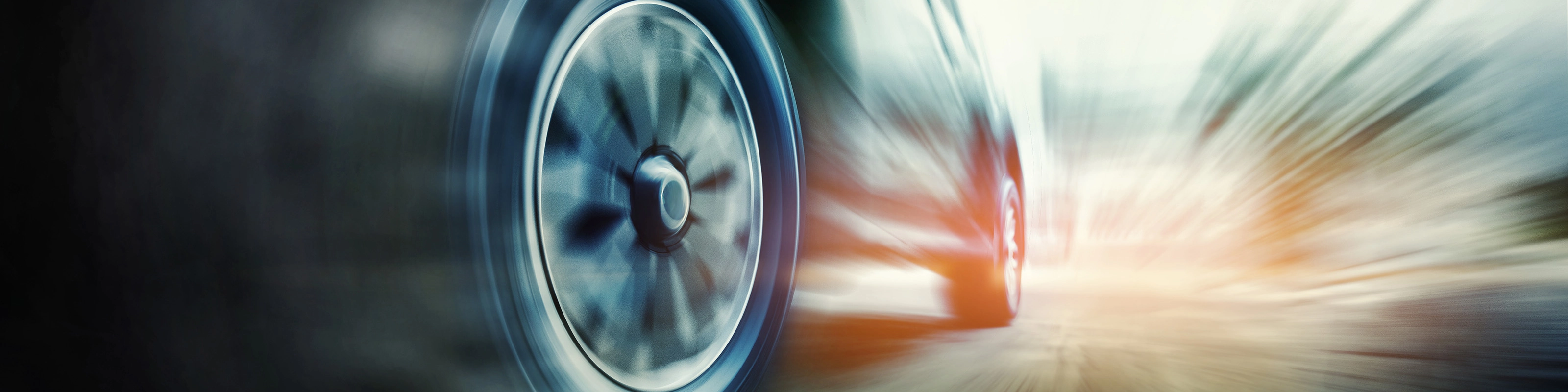 Close-up of a speeding car tire in motion blur on the road.