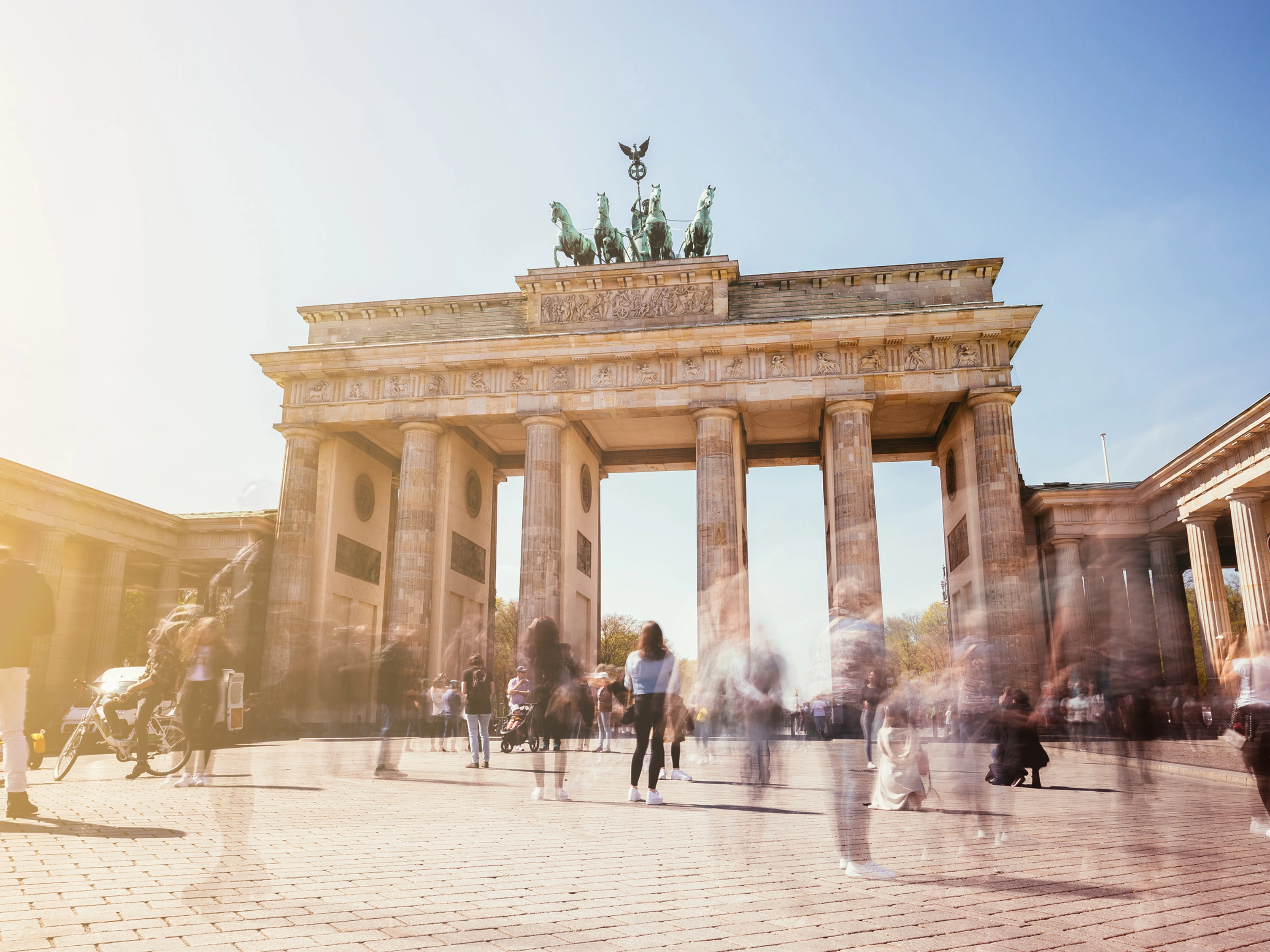 Brandenburg Gate in Berlin with many people in motion on a sunny day.