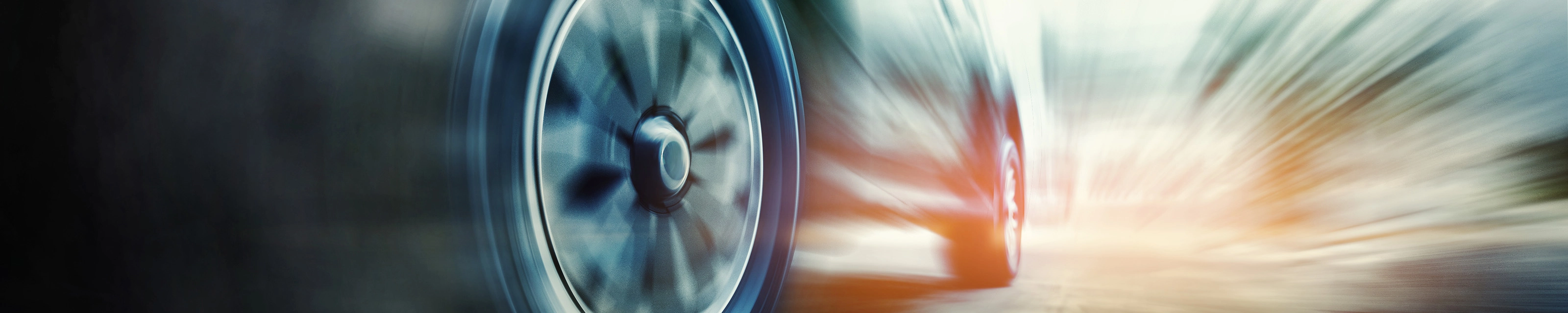 Close-up of a speeding car tire in motion blur on the road.