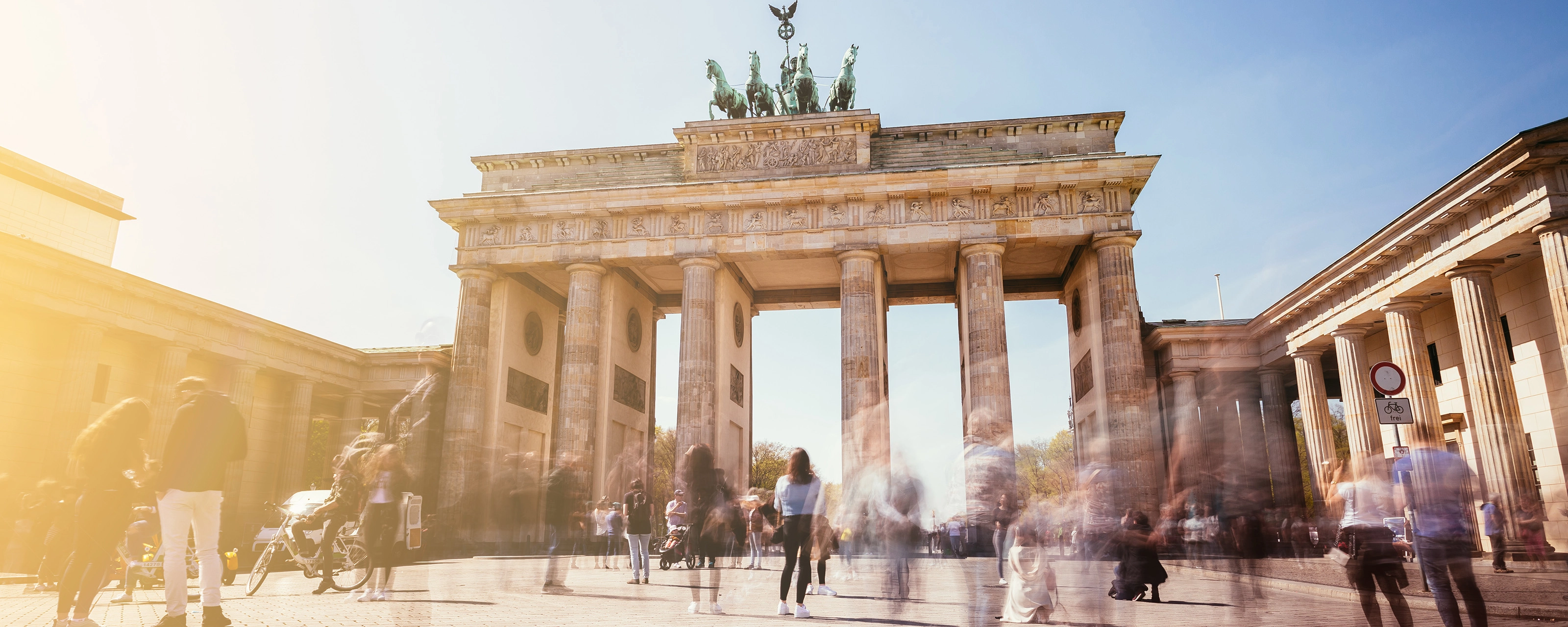 Brandenburg Gate in Berlin with many people in motion on a sunny day.