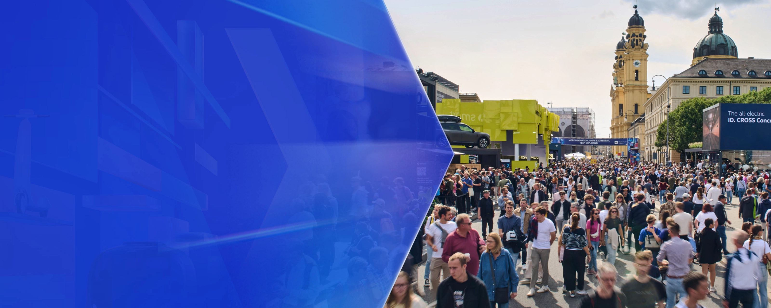 Large crowd at an outdoor mobility fair with exhibition booths and historic buildings in the background.