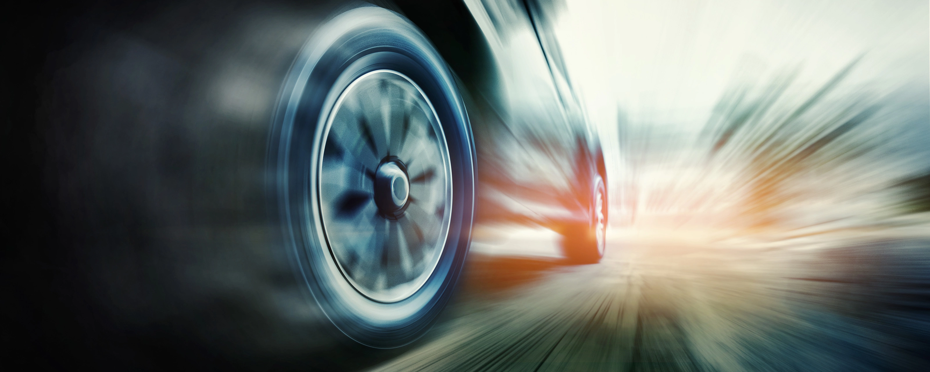 Close-up of a speeding car tire in motion blur on the road.