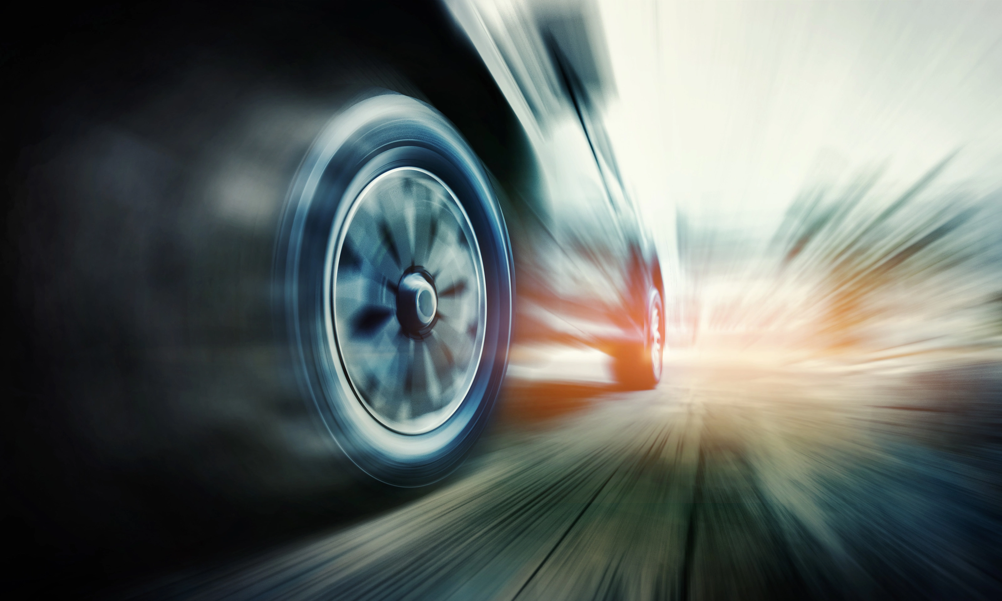Close-up of a speeding car tire in motion blur on the road.