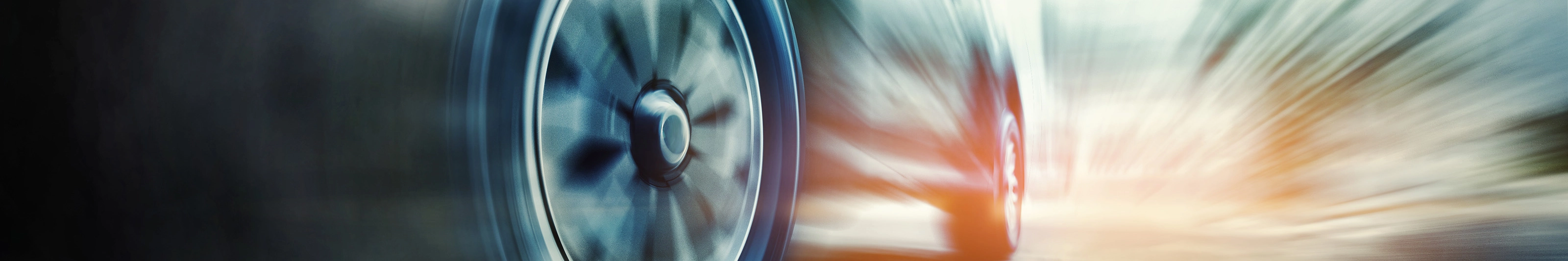 Close-up of a speeding car tire in motion blur on the road.